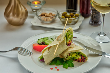 Vegetable rolls. Pancakes with vegetables. Pita bread wrapped in cabbage, cucumber, avocado, carrots, cabbage, salad. The dish is decorated with onion rings, cucumber slices, sweet red pepper and mint