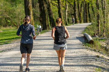 Freizeitsport: Aktiv an der Isar in München am Flaucher - zwei junge aktive Frauen beim Laufen