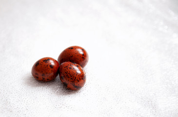 three red quail eggs on a white background
