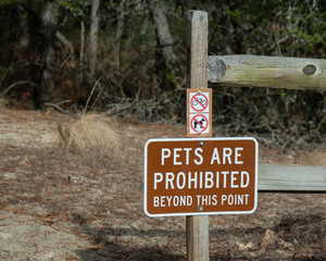 Brown metal pets are prohibited sign with two smaller no pets and no bikes symbols mounted on wood...