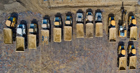 Aerial drone view on heavy dump trucks at the construction site.