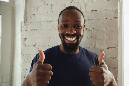 African-american Musician On White Brick Wall Background, Cheerful And Happy. Resting After Online Concert, Showing Nice Gesture, Smiling. Human Emotions, Art, Music, Support On Quarantine Concept.