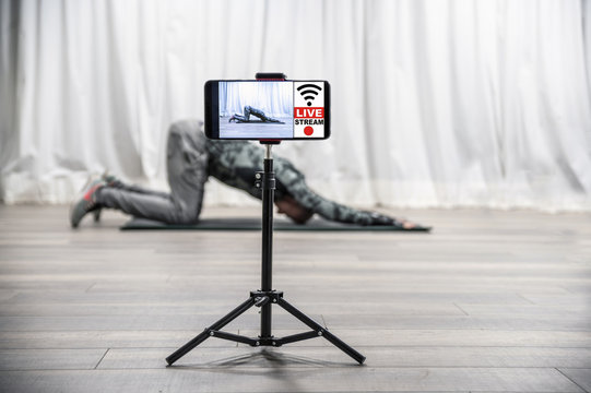 Stay Home For Corona Virus. Home Fitness Workout Class Live Streaming Online. Man Doing Strength Training Cardio Aerobic Exercises Live On His Smartphone For The Sportive Follower On The Social Media.