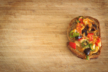Little homemade pizza made from brown bread on wooden chopping board. Left of chopping board is copy space. 