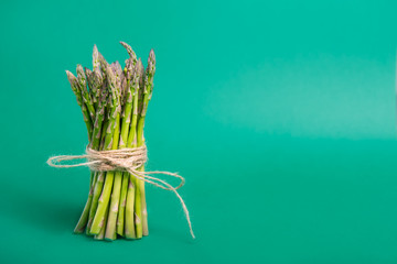 Bunch of fresh asparagus standing on green background. Vegetarian and vegan diet. Veganism. Sustainable lifestyle, plant-based foods. Copy space.