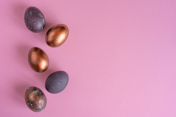 Colored painted pearl chicken eggs of violet, golden color on pink background. Minimalistic creative idea