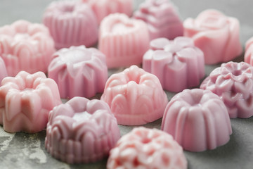 the small handmade soap is laid out in the form of a square in even rows on a concrete background. Lots of pink soap. Close-up