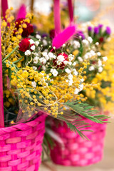 Beautiful colorful spring background with flowers in a wicker pink baskets, close-up. Copy space for greeting postcard