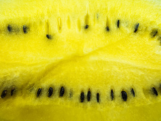 A close-up photo of the pulp of a ripe yellow watermelon with black seeds