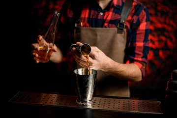 Fototapeta na wymiar Close-up male barman pours cocktail from bowl into metal martini glass.