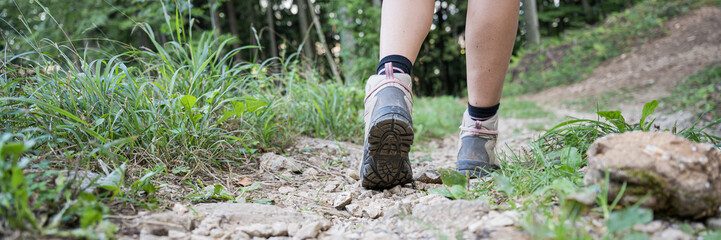 Female legs in hiking boots on forest trail