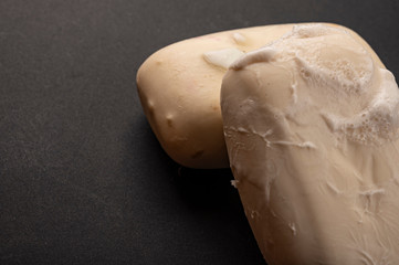 Two pieces of toilet soap on a black background. Close up. Regular hand washing with soap is a...