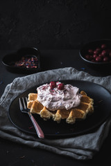 Belgian waffle with cranberry cream on a black plate