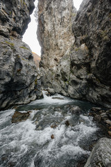 Fototapeta na wymiar A stormy mountain river flows through a gorge of mountains. Nature.