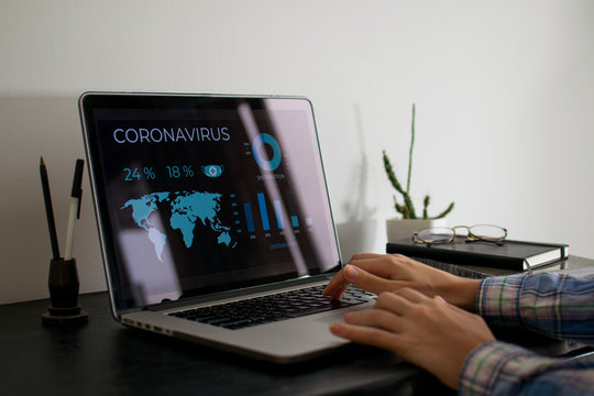 Manos trabajando en computadora con gr&aacute;ficos de Coronavirus. Escritorio minimalista negro.