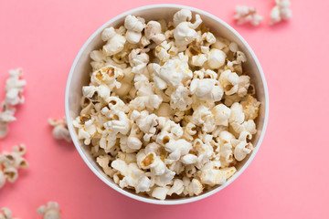 Popcorn in a bowl on pink background, top view