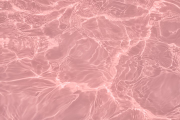 Fototapeta premium Closeup of calm clear water surface with water splashes in trendy pink color. Swimming pool water texture. Trendy fresh abstract nature background. 2020 color trend concept.