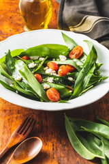 Fresh salad with wild garlic,tomatoes and feta cheese on plate.