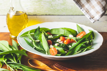 Fresh salad with wild garlic,tomatoes and feta cheese on plate.