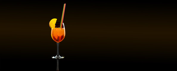 aperol syringe in glass with orange, summer cocktail with tubules, over black background