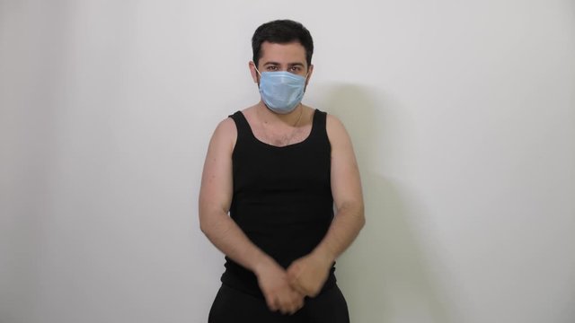 Angry young Caucasian man in a medical mask shows to the camera that someone has come to an end white background Covid19 Coronavirus