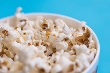 Popcorn in a bowl on blue background.