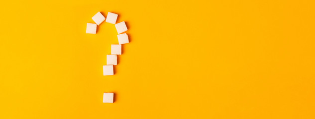 white sugar cubes shaped as a question mark on orange background. Top view. Diet  unhealthy sweet...