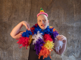 attractive girl with shaved bald head in a feather-cloak of LGBT colors. Beautiful middle-aged woman with cancer fell ill without hair in carnival cap LGBTQ
