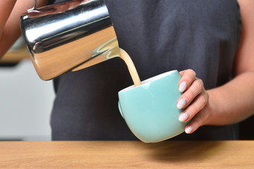 Barista girl makes coffee and pours it into a mug. Small business and addiction concept