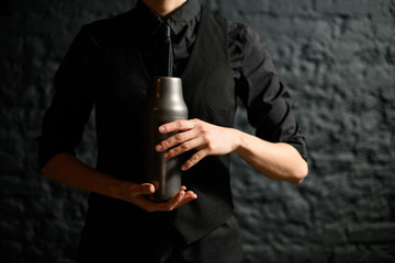 Close-up bartender holding steel shaker in her hands