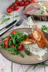 bacon and cheese pork rolls with tomatoes and arugula on a wooden white table in a restaurant