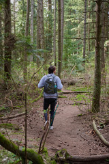 Obraz premium Teenager walking on the forest with a backpack and a water bottle
