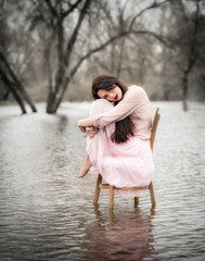 Self-isolation in quarantine. The girl sits on a chair in the water. Pandemic, flood