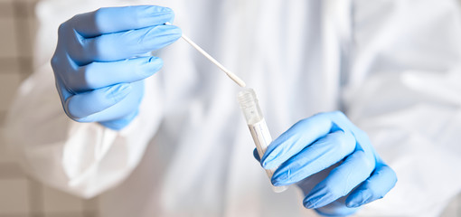 Doctor holding swab test tube for 2019-nCoV analyzing. Coronavirus test. Blue medical gloves and...