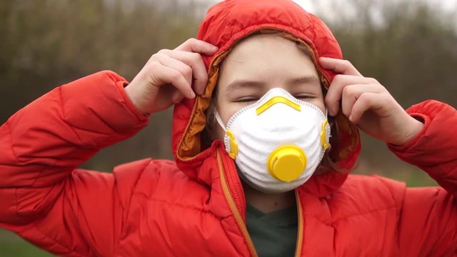 Curly-haired schoolboy takes off his protective medical mask and breathes air and smiles. End quarantine coronovirus covid-19