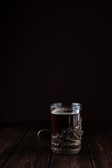 one glass of tea in a vintage cup holder on a wooden table, concept of restaurant menu with copy space