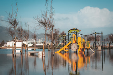 Fototapeta na wymiar Playground for kids in water with reflection after storm that caused flooding. Natural disaster concept