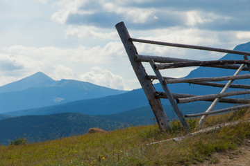 part of a wooden fence against the backdrop of Mount Petros. Carpathian landscape. Ukraine