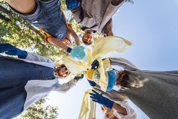 Group of activists friends throw a lot of garbage in a bag. Bottom-up shooting