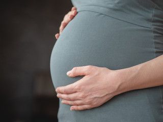 Close-up of a pregnant woman lovingly caressing her belly