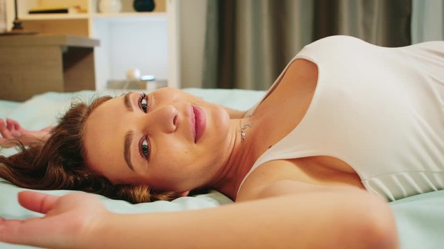 Close up of beautiful young woman in pajamas falling back on bed