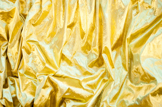 Full Frame Background Of Shimmery Gold Fabric With Textured Rumples And Wrinkles