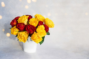 Bouquet of red and yellow roses in white vase. Toned image. Copy space. Holiday background