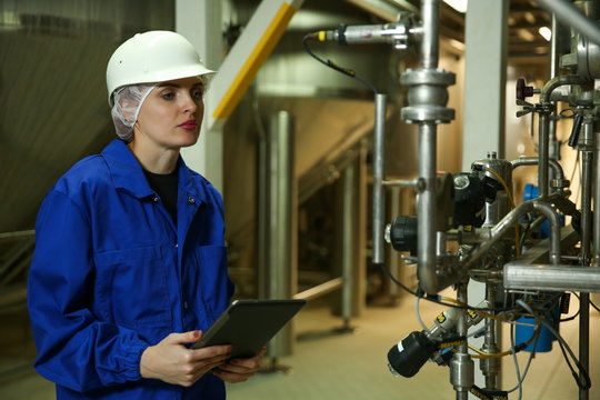 Female Engineer Is Holding Tablet And Conducting An Inspection In A Production Hall At A Food Factory