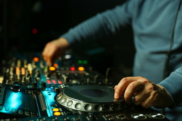 dj is mixing tracks at party in night club. disc jockey playing music on the modern turntable close...