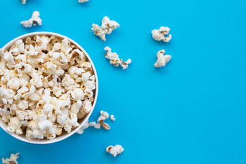 Popcorn in a bowl on blue background, top view