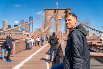 Young man sitting on a  Brooklyn Bridge with a magical Manhattan island view.