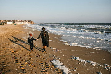mother and child, running on the beach from waves.
