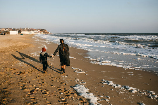 mother and child, running on the beach from waves.