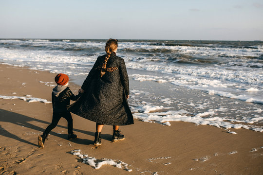 mother and child, running on the beach from waves.